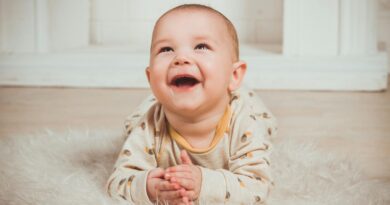 Joyful baby lying on a fluffy rug, smiling and looking upwards indoors.