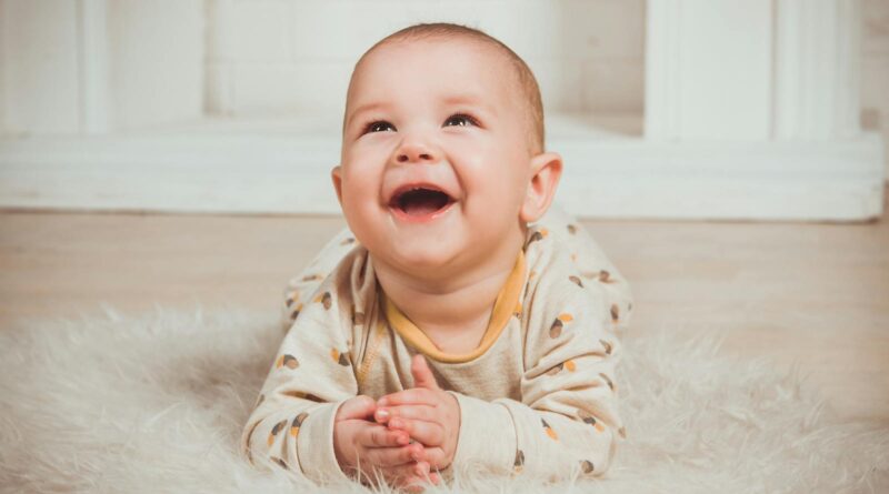 Joyful baby lying on a fluffy rug, smiling and looking upwards indoors.