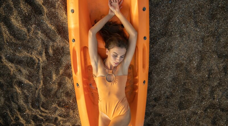 woman in yellow swimsuit lying on orange inflatable bed